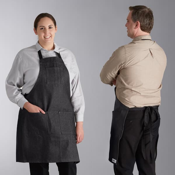 a man wearing a tan shirt and black apron