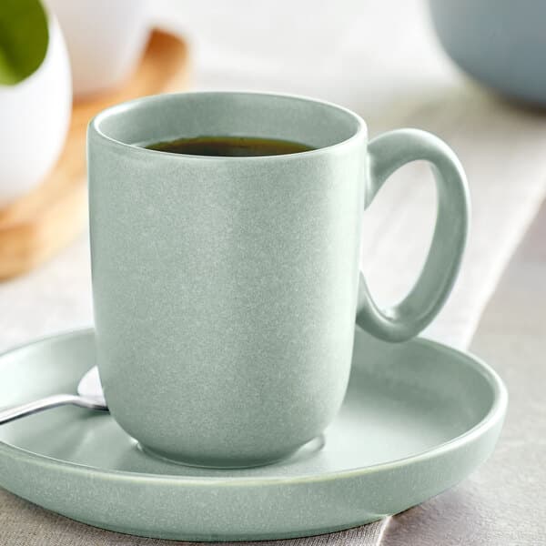 An Acopa Harbor Blue porcelain cup on a saucer with a spoon.