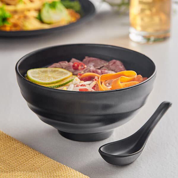 A black Acopa Izumi melamine bowl with food and a spoon.
