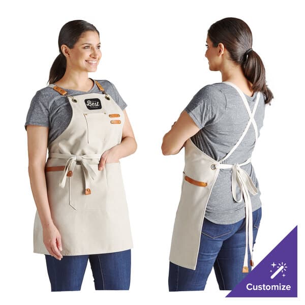 A woman wearing a white Acopa Hazleton canvas cross-back bib apron with 3 pockets.