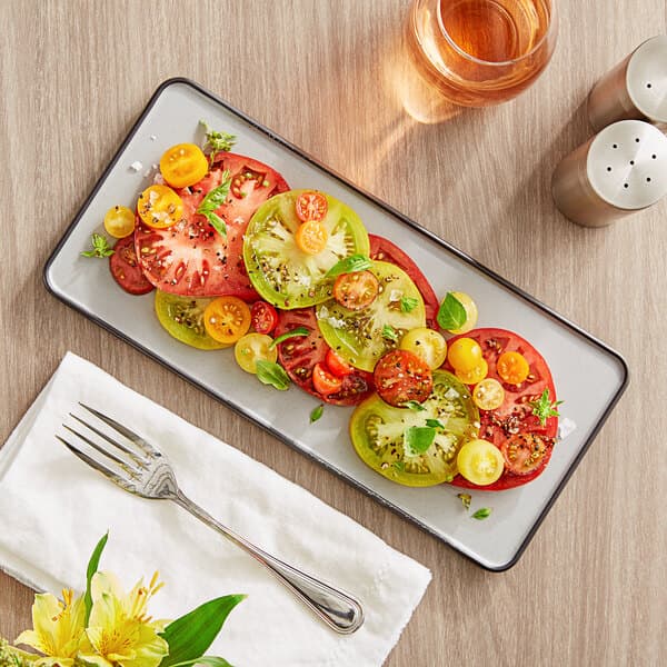 An Acopa rectangular melamine tray with tomatoes and basil on it.