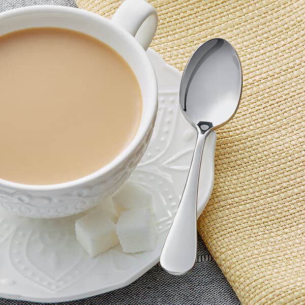 A cup of coffee with an Acopa Vittoria stainless steel demitasse spoon on a saucer.