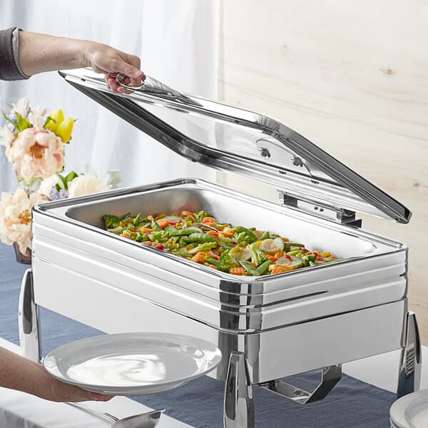 A person holding a plate of food in a Acopa Manchester chafer.
