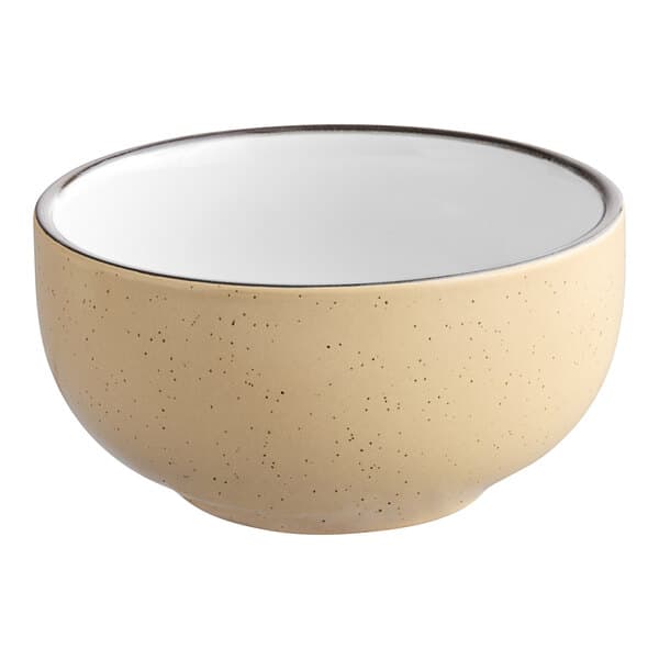 A close-up of an Acopa Harvest Tan stoneware bowl with a speckled surface and black rim.