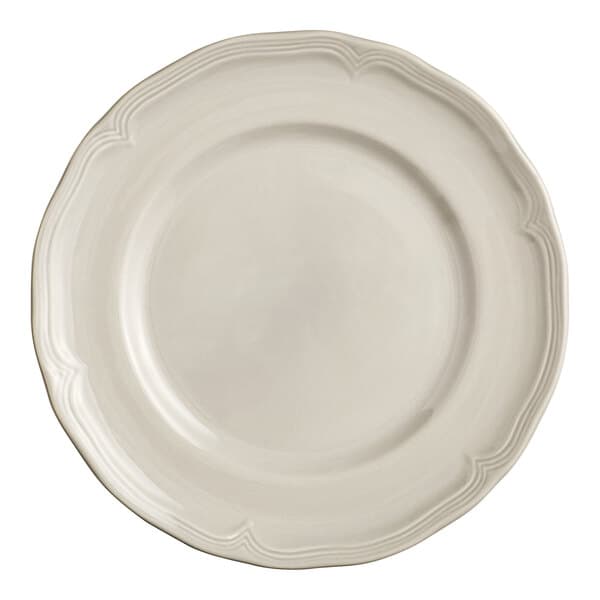 A close-up of an Acopa Condesa white porcelain plate with a scalloped white rim.