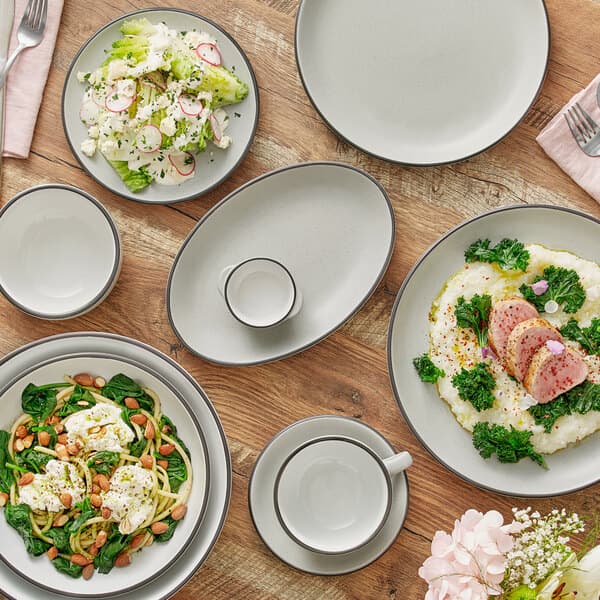 A table set with Acopa Embers grey matte stoneware plates, bowls, and silverware.