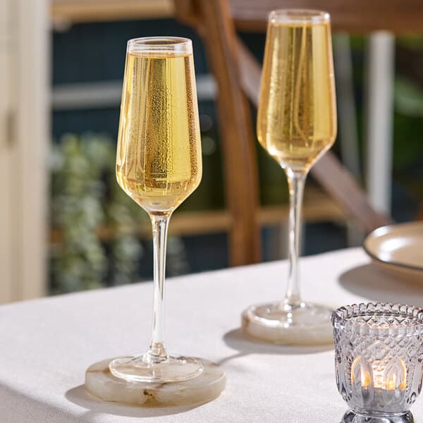 Two Acopa Silhouette champagne flutes on a table with candles.