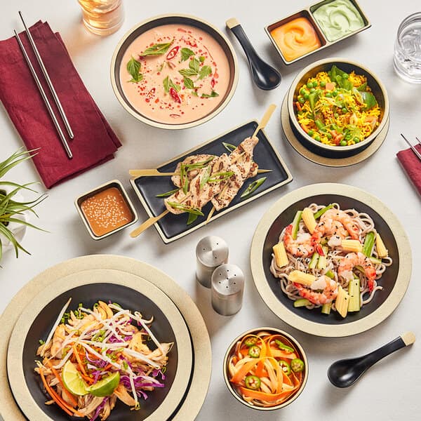 An Acopa Ugoki melamine plate with a bowl of noodles and chopsticks on a table in an Asian restaurant.