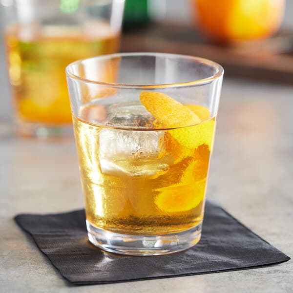 A stackable Acopa Select rocks glass with ice and an orange slice.