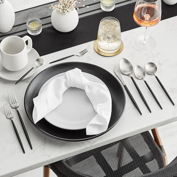 A black and white table set with Acopa Odin stainless steel dinner knives.