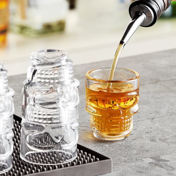 A Acopa skull shot glass with a skull shaped drink being poured into it.