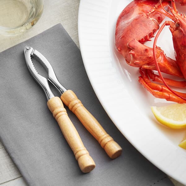 A plate of lobster with an Acopa lobster cracker next to a lemon slice.