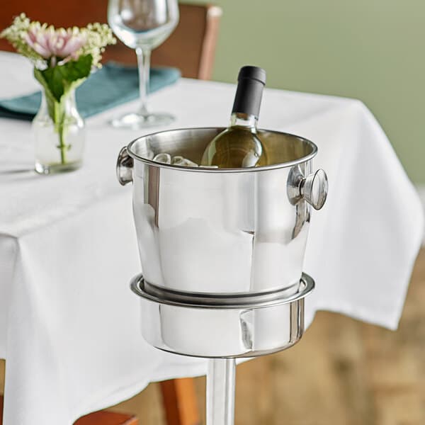 An Acopa wine bucket holding a wine bottle on a table.
