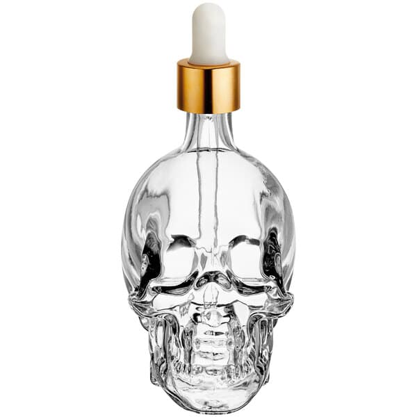 An Acopa clear glass skull bitters bottle with a dropper.