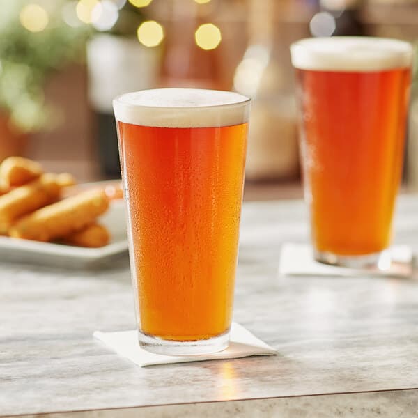 An Acopa Select mixing glass filled with beer on a table.