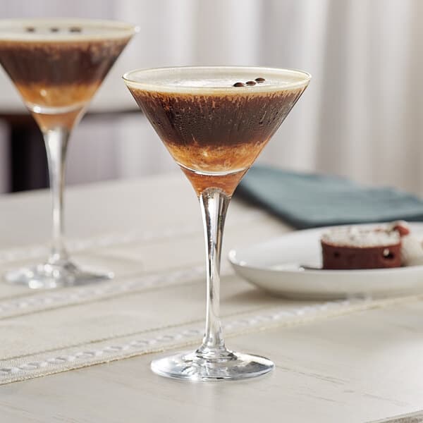 Two Acopa Select martini glasses on a table with drinks in them.