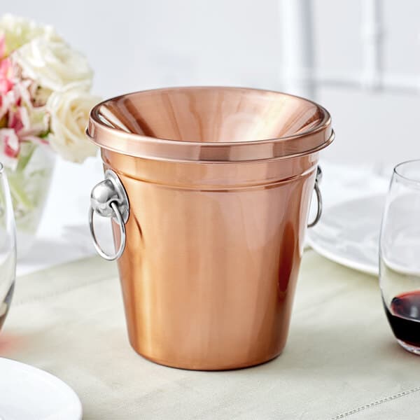 An Acopa copper wine tasting spittoon on a table with wine glasses.