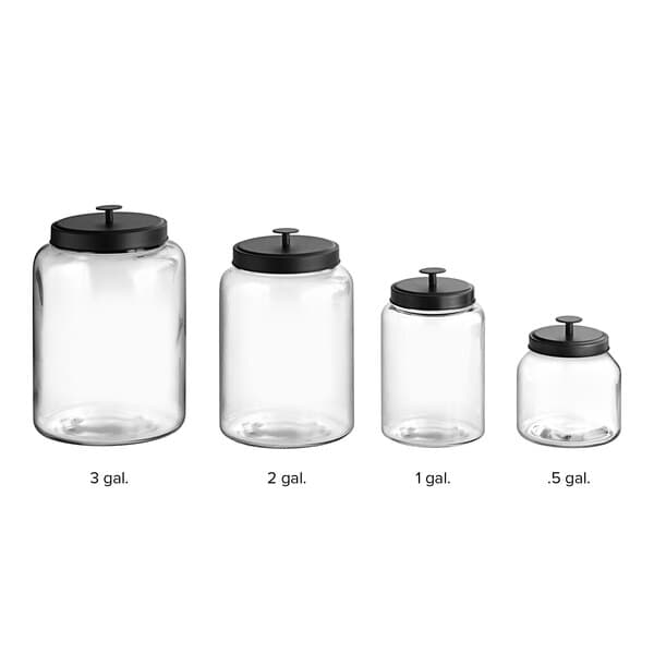 A group of Acopa clear glass jars with black lids on a counter.