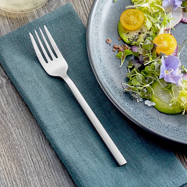 A plate of food with a salad and an Acopa Phoenix satin stainless steel salad fork.