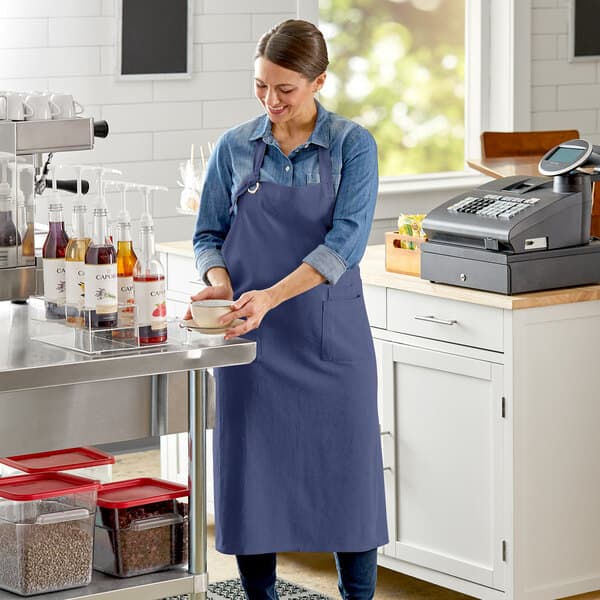 A woman wearing an Acopa Ashville Ocean Linen bib apron with 2 pockets.