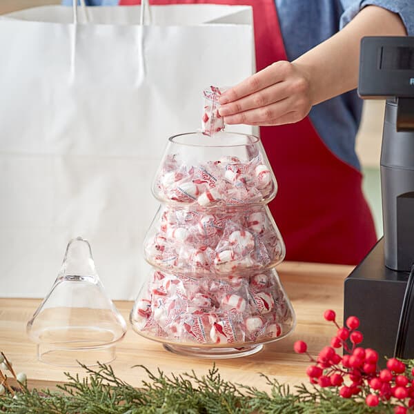 A person putting candy in an Acopa glass pine tree jar with a cork lid.