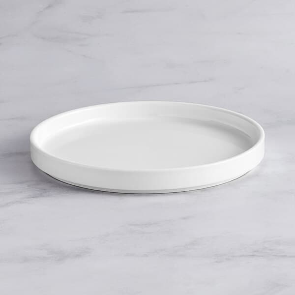 An Acopa Lore bright white porcelain plate on a marble surface.