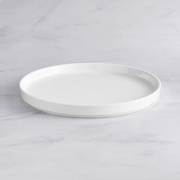 An Acopa Lore bright white porcelain plate on a marble surface.