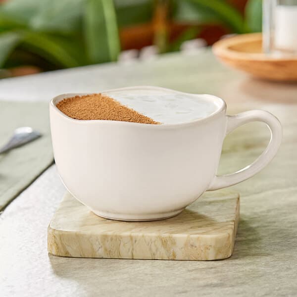 An Acopa Highlands white china cup filled with brown powder on a wooden table.