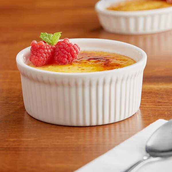 A white Acopa fluted porcelain dish filled with creme brulee and raspberries.