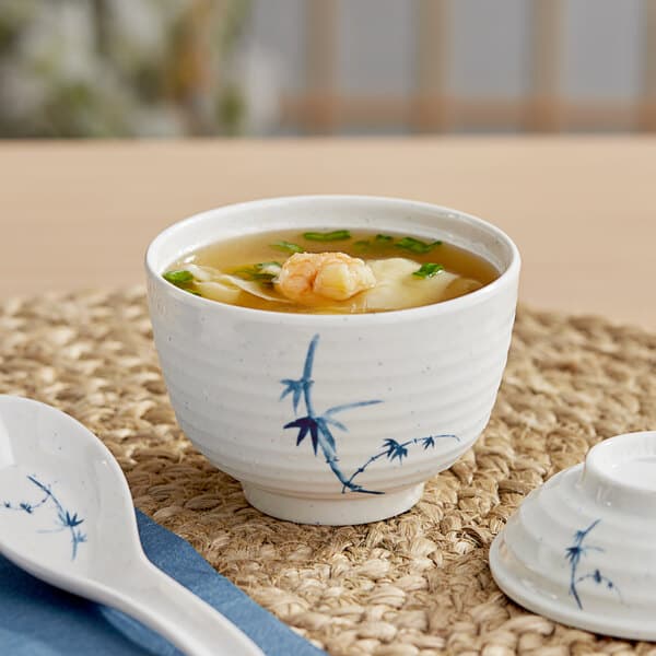 A close-up of a white Acopa Biru melamine miso bowl filled with soup with a spoon.