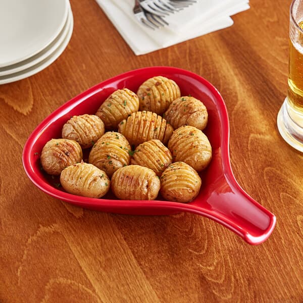 An Acopa red stoneware bowl filled with potatoes on a table.