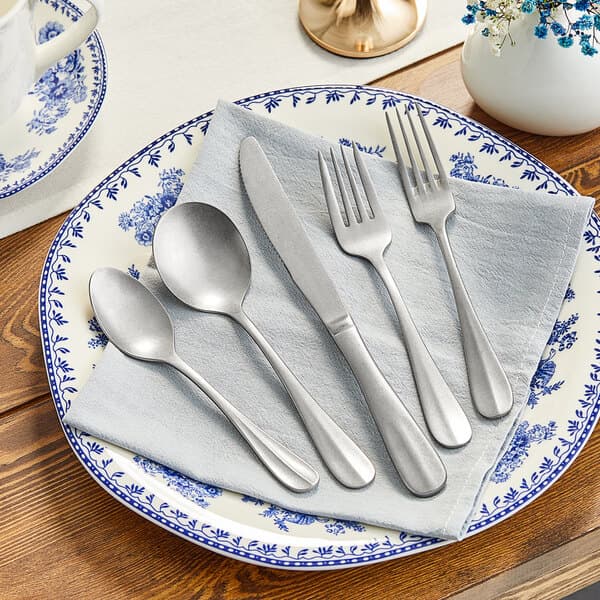 A plate with Acopa stainless steel flatware samples on a white towel.