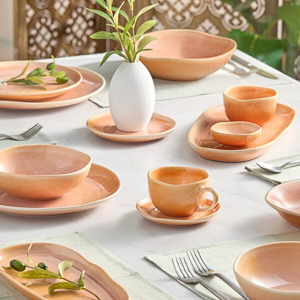 An Acopa Primrose Peach China sauce cup on a table set with orange dishes.
