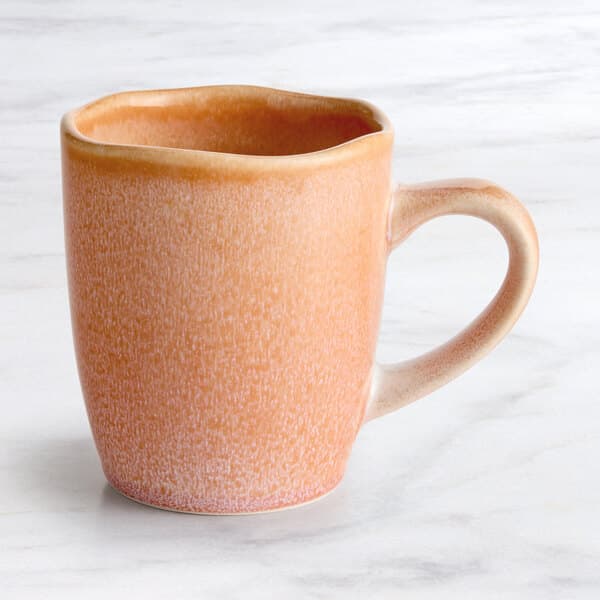 An Acopa Primrose Pink china mug on a white surface.