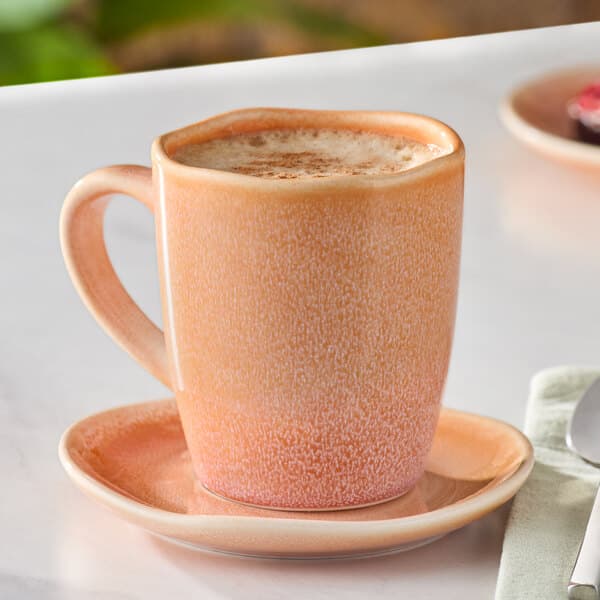 A Primrose Peach Acopa Highlands china mug of coffee on a saucer.
