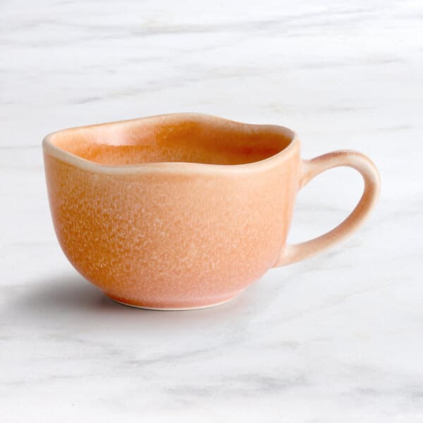 An Acopa Primrose Pink China cup sitting on a marble surface.