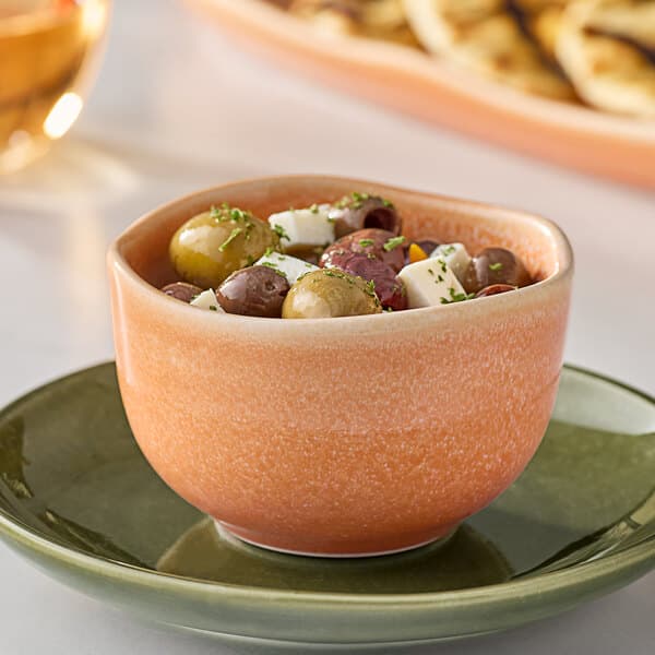 An Acopa Primrose Peach china bouillon cup filled with food on a table.