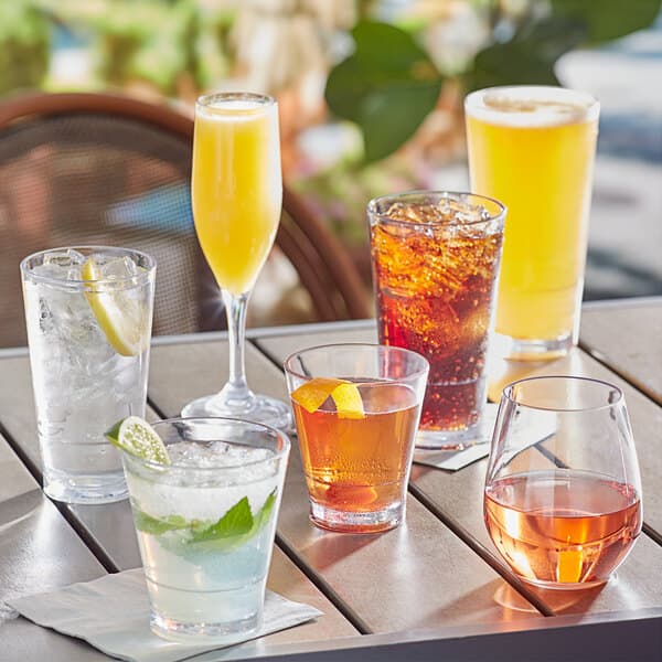 Acopa Endure Tritan plastic champagne flutes on a table with a variety of drinks.