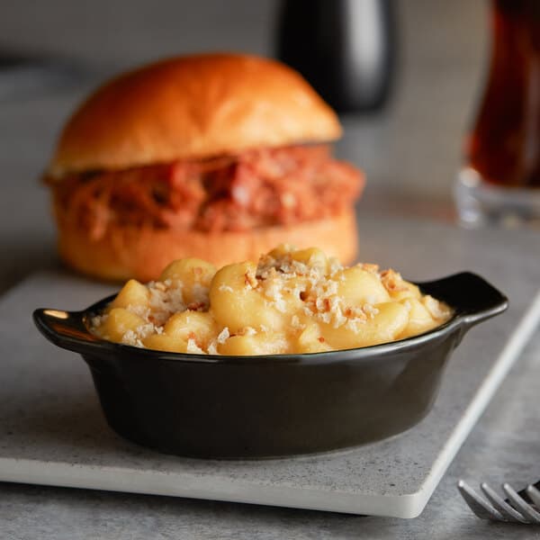 A bowl of macaroni and cheese in an Acopa Keystone mini rarebit dish next to a sandwich.