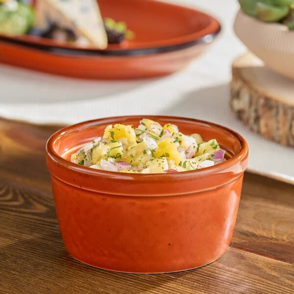 An Acopa Sedona Orange porcelain ramekin filled with fruit salad on a table.