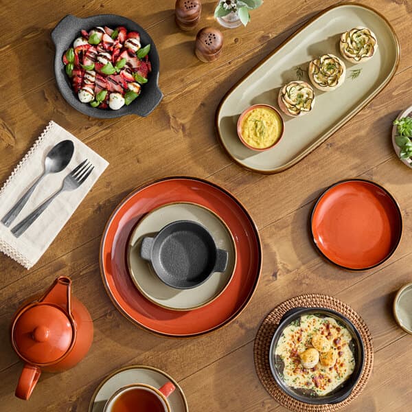 An orange Acopa Keystone ramekin on a table with food.