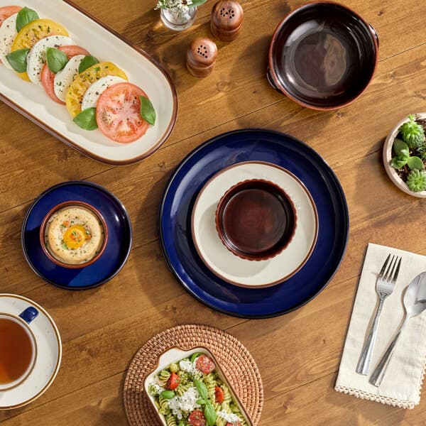 A table with Acopa Keystone ramekins, plates, and bowls on it.