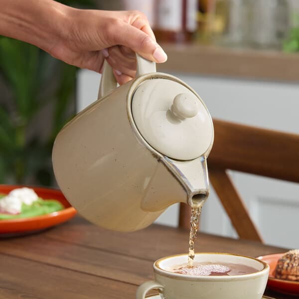 A person pouring water into a Granite Gray Acopa Keystone teapot.