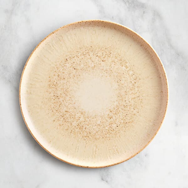 An Acopa Cape beige porcelain plate with a white rim on a marble surface.