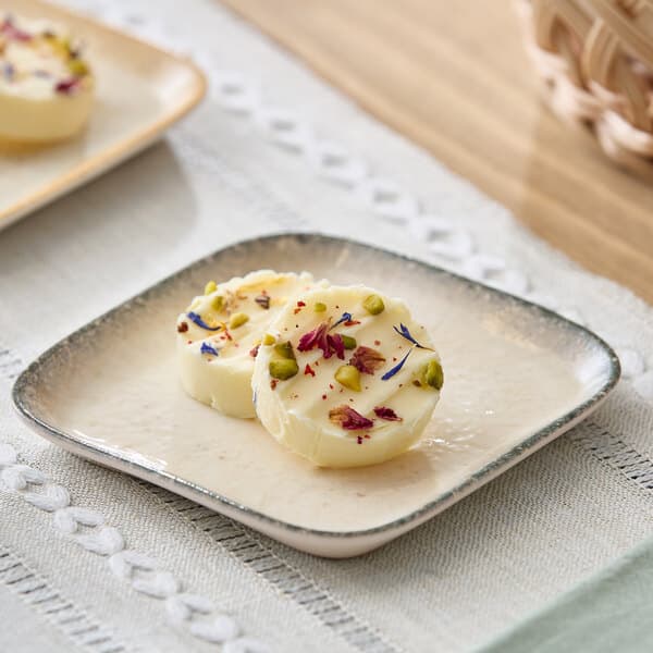 A square gray porcelain butter dish holding two pieces of garnished butter.