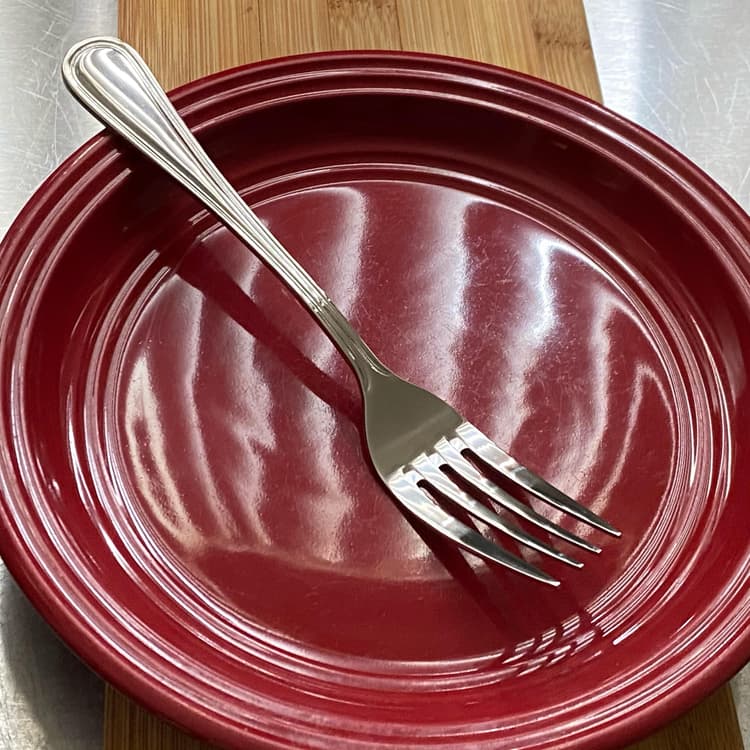 Acopa Edgeworth 7 1/4" 18/8 Stainless Steel Extra Heavy Weight Dinner Fork in a plate.