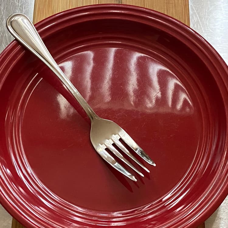 Picture of Acopa Edgeworth 6 3/4" 18/8 Stainless Steel Extra Heavy Weight Salad Fork in a plate.