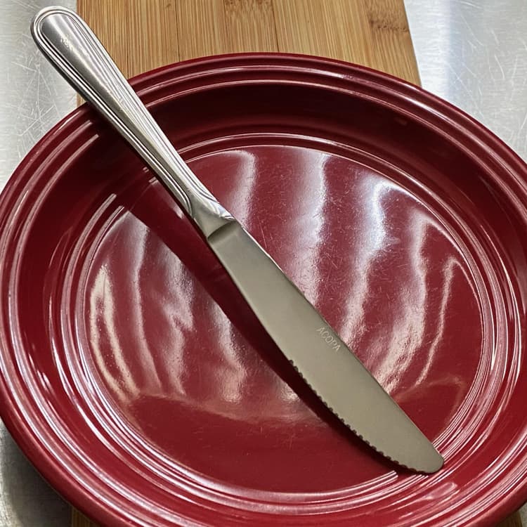 Picture of the Acopa Edgewood / Edgeworth 8 1/2" 18/8 Stainless Steel Extra Heavy Weight Dinner Knife in a plate.