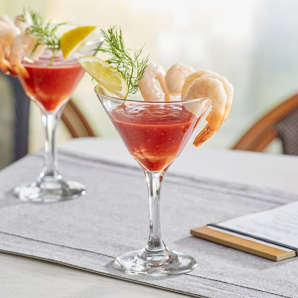 A pair of Acopa cocktail glasses filled with shrimp and lemon slices on a table.