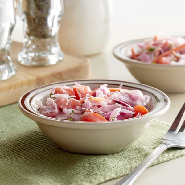 Two Acopa brown speckle stoneware monkey dishes filled with salad on a table.